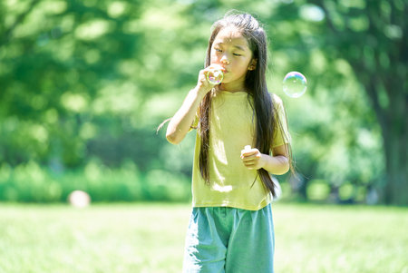 girl playing with soap bubbles in the parkの写真素材