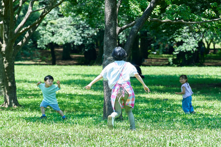 A woman in an apron with children playing chasing in the parkの写真素材