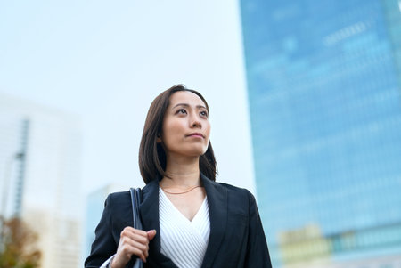 Business woman looking up at the sky in the townの写真素材