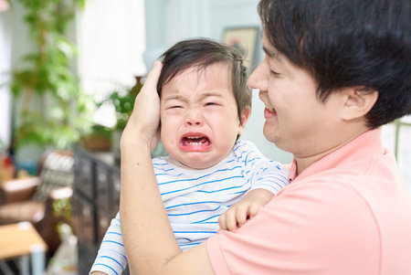 Crying baby and parents holding each otherの写真素材