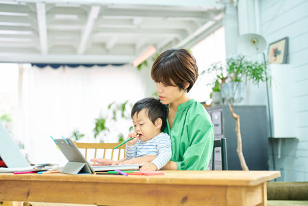 A woman working from home with a babyの写真素材