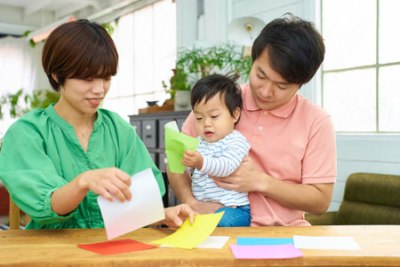 Parent and child playing origami indoorsの写真素材