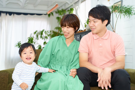 A family of three smiling and relaxing indoorsの写真素材