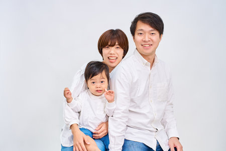 Family smiling and lining up in front of white backgroundの写真素材