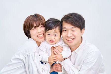 Family smiling and lining up in front of white backgroundの写真素材