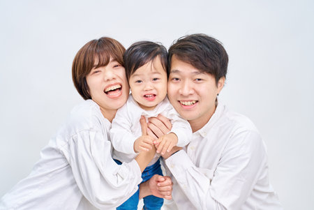 Family smiling and lining up in front of white backgroundの写真素材