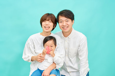 Portrait of a family of three in front of a blue backgroundの写真素材
