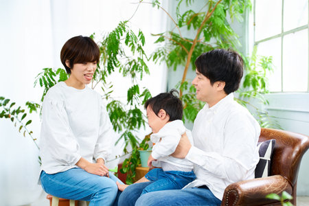 A family of three smiling and relaxing indoorsの写真素材