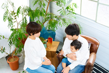 A family of three smiling and relaxing indoors