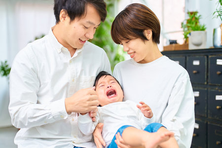 Crying baby and parents holding each otherの写真素材