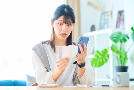A young woman with a surprised expression holding a receipt in her handの写真素材