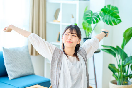 A young woman taking a deep breath in a bright casual spaceの写真素材