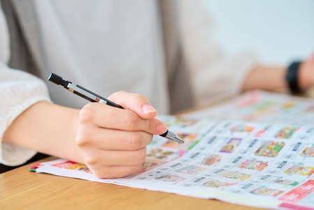 Hand of a woman checking an advertising booklet on the tableの写真素材