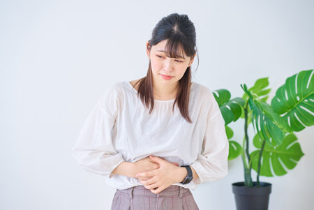 young woman suffering from abdominal pain indoorsの写真素材