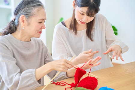 Senior woman and young woman knitting in the roomの写真素材