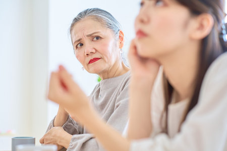 A senior woman looking at a young woman with a grim expression in the roomの写真素材