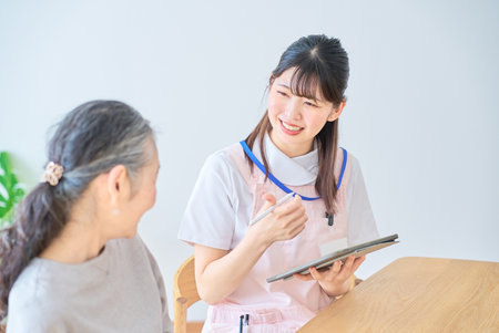 Young woman in apron and senior woman having a conversation at homeの写真素材