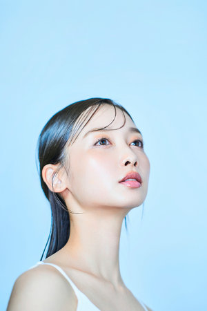 Asian young woman and light blue backgroundの写真素材