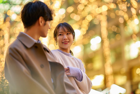A woman happily talking to a man in an illuminated cityscapeの写真素材