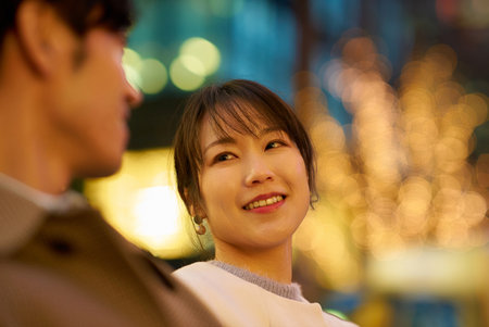 A woman happily talking to a man in an illuminated cityscapeの写真素材