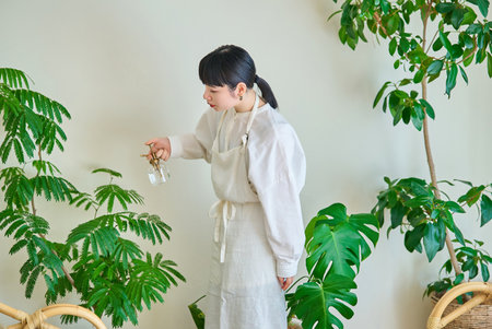 A young woman watering the houseplants in the room