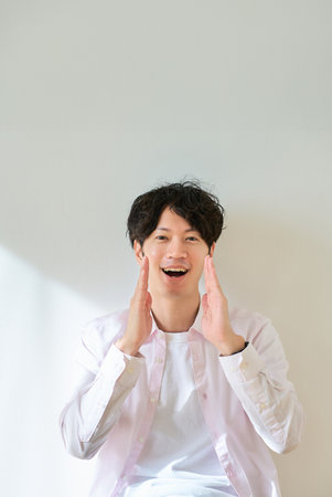 Portrait of a young man cheering in front of a white backgroundの写真素材