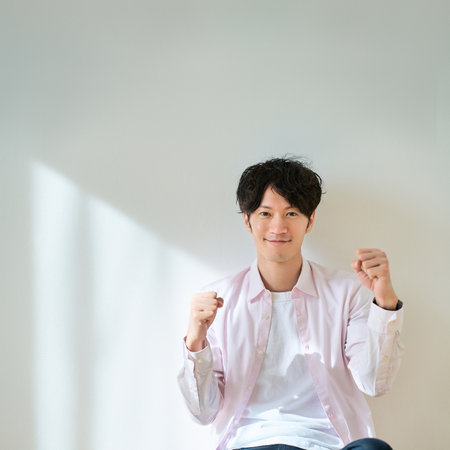 A young man doing a fist pump in front of a white backgroundの写真素材