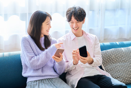 A man and a woman looking at smartphones in the roomの写真素材