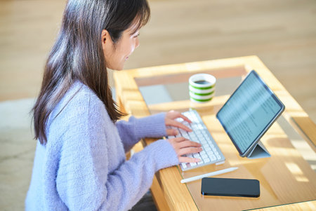 A woman working on a computer in a casual roomの写真素材