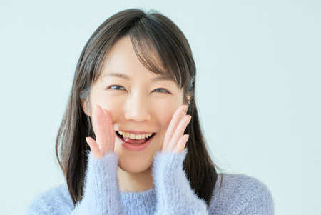 Portrait of a young woman cheering in front of white backgroundの写真素材