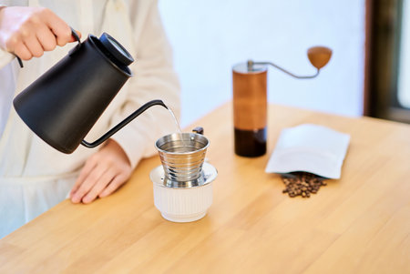 Young woman with apron making coffee in the kitchenの写真素材