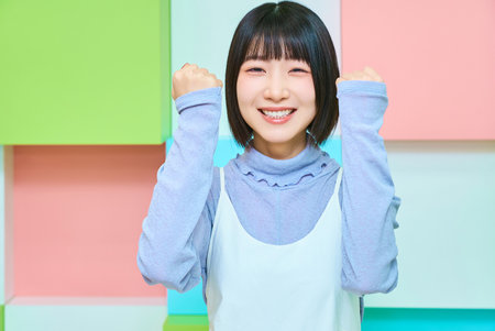 Colorful background with young woman doing fist pumpの写真素材