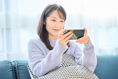 Young woman looking at smartphone screen in the roomの写真素材
