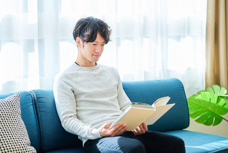 young man reading a book in the roomの写真素材