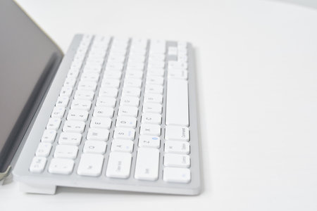 Close-up of wireless keyboard from the side on a white tableの写真素材