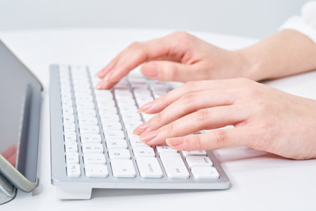 Hands of a woman typing on a keyboardの写真素材