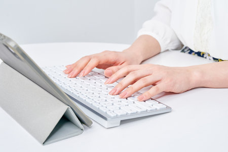 Hands of a woman typing on a keyboardの写真素材