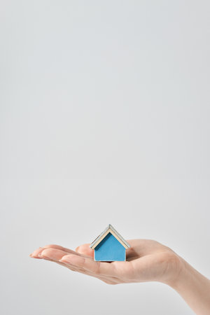A house model held in the palm of a woman's hand and white backgroundの写真素材