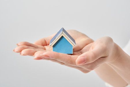 A house model held in the palm of a woman's hand and white backgroundの写真素材