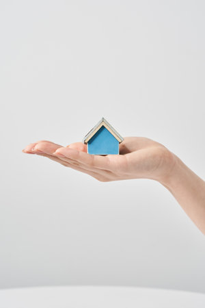 A house model held in the palm of a woman's hand and white backgroundの写真素材