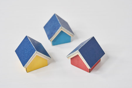 Models of multiple houses lined up on a white tableの写真素材
