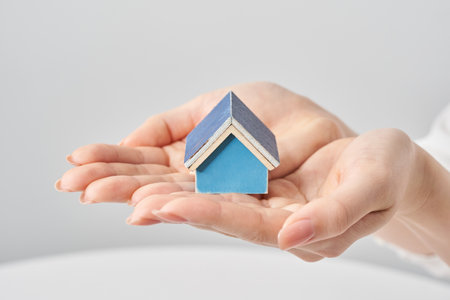 A house model held in the palm of a woman's hand and white backgroundの写真素材