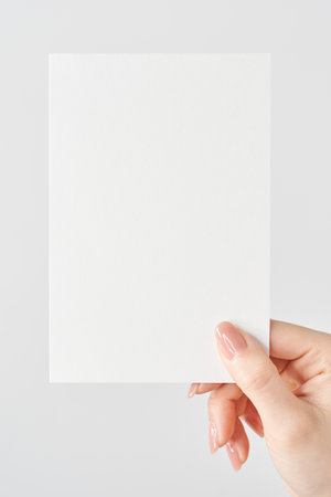 Woman's hand holding white paper and white backgroundの写真素材