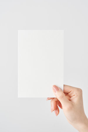 Woman's hand holding white paper and white backgroundの写真素材