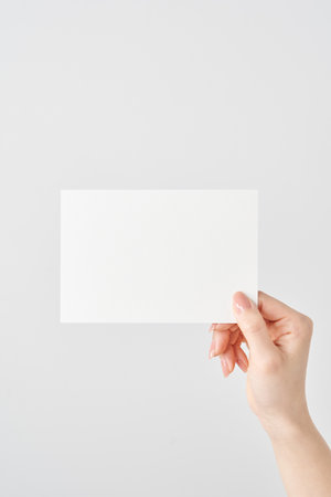 Woman's hand holding white paper and white backgroundの写真素材