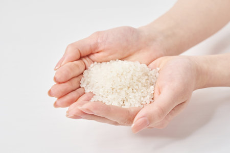 A cup of rice in the hand and white backgroundの写真素材