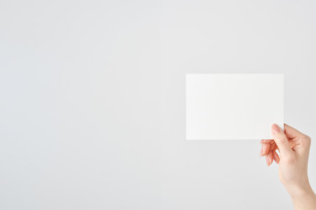 Woman's hand holding white paper and white backgroundの写真素材
