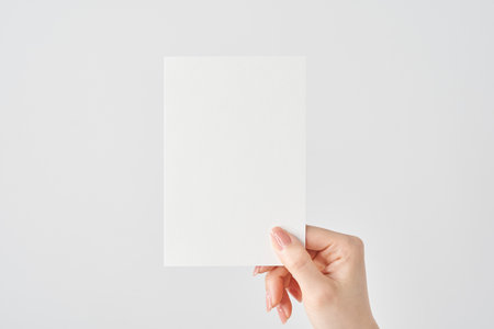Woman's hand holding white paper and white backgroundの写真素材