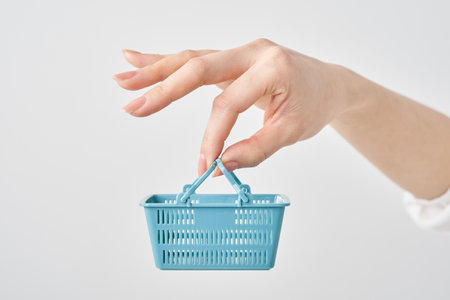 Hand of a woman holding a small shopping basketの写真素材