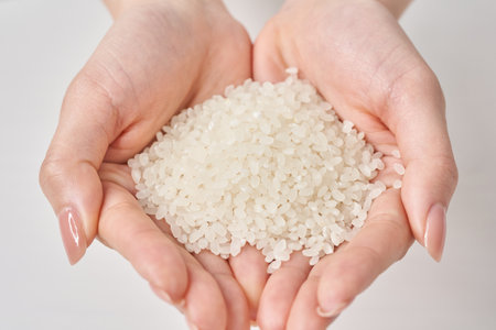 A cup of rice in the hand and white backgroundの写真素材